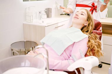 Diş hekimliğinde dişçi koltuğunda diş muayenesi yapan güzel genç bir kadın. Sağlık dişleri konsepti..