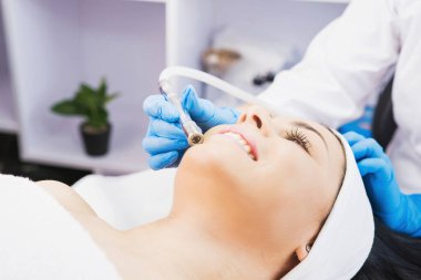Kozmetik uzmanı, güzellik salonundaki bir kadına sivilcelere ve siyah noktalara karşı mikro dermabrüksiyon uyguluyor..