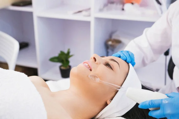Nahaufnahme Foto einer professionellen Kosmetikerin, die in der Kosmetologie-Klinik ein darsonales elektrisches Gesichtsvakuum durchführt und blaue Handschuhe trägt. — Stockfoto