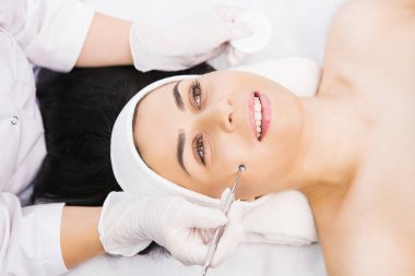 Profesyonel kozmetik uzmanı, kozmetik kliniğinde bir kadına dermapen prosedürü uygular, yüz estetiği, tek kaşıkla elle mekanik yüz temizleme, yağ prosedürü kavramını kaldırma,.