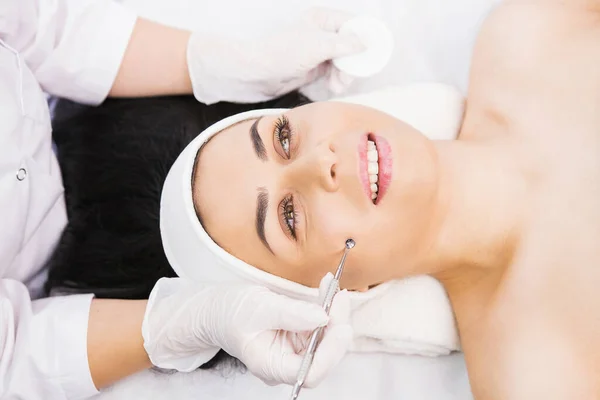 Professionelle Kosmetologe führt Dermapen-Verfahren in der kosmetologischen Klinik für eine Frau, Gesicht kosmetische, manuelle mechanische Gesichtsreinigung mit uno Löffel, Entfernen von Fett Prozedurkonzept. — Stockfoto
