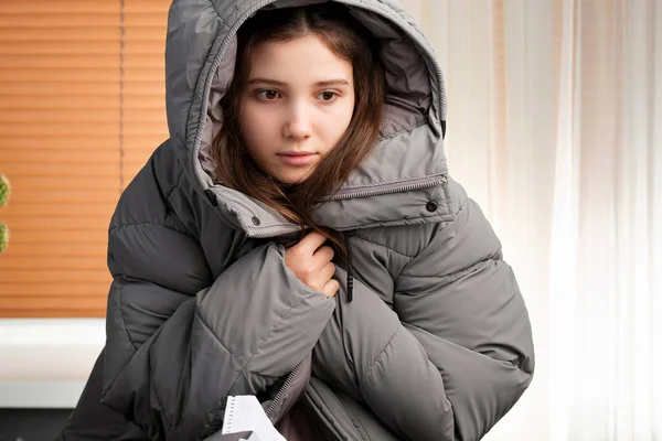 Close-up foto van een jong meisje dragen winterjas binnen, het uitschakelen van de verwarming in het huis als gevolg van niet-betaling van rekeningen. — Stockfoto