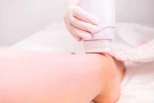 Procedure di cera sulle gambe fatte in un salone spa da un terapeuta caucasico con i guanti a una cliente donna nel salone di bellezza di cosmetologia. — Foto Stock