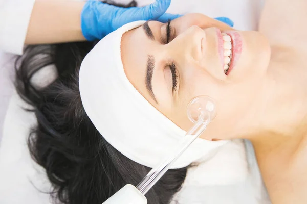 Foto von oben von einer glücklich lächelnden Frau in einer Schönheitsklinik, die eine Gesichtsmassage zur Verjüngung erhält. — Stockfoto