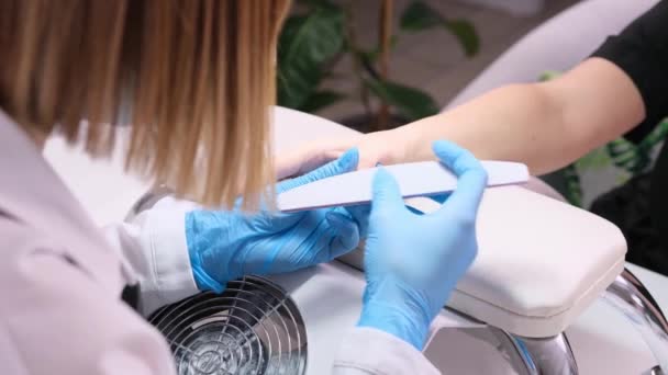 Manicure specialist in schoonheidssalon clearing cuticula professionele nagel bestand voor manicure in een schoonheidssalon dragen blauwe beschermende handschoenen. — Stockvideo