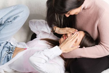 Birbirini seven iki kız arkadaş, biri elleri kapalı, diğeri ona bakıp gülümsüyor..