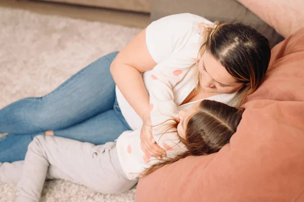 Foto de arriba de dos personas niña y su madre sentadas en el suelo abrazándose juntas y pasando un día maravilloso juntas. — Foto de Stock