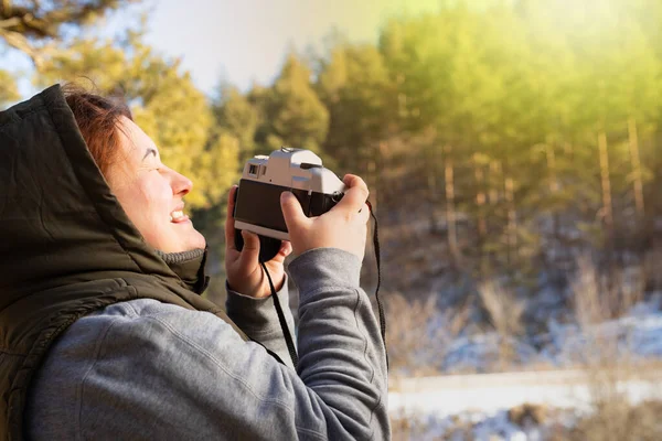Photographe femme chaudement habillée prenant des photos de la nature étant à l'extérieur au lever du soleil dans la forêt avec les yeux fermés. — Photo