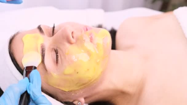 Cosmetologist em luvas de proteção esfregando no rosto da mulher cliente usando um pincel, conceito de cuidados com a pele. — Vídeo de Stock