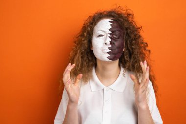 Katar futbol takımının ulusal bayrağında kırmızı saçlı ve yüzü resmedilmiş Katar taraftarı bir kadının resmi..