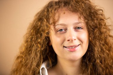 Güzel, güzel, çekici, kızıl saçlı bir kadının, altın rengi bir arka planda sakin ve parlak bir şekilde çekilmiş fotoğrafını çek..