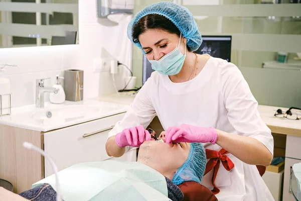 Ein gutaussehender Patient liegt im Zahnarztstuhl und hält seinen Mund offen, während der Zahnarzt seine Zahngesundheit untersucht. — Stockfoto