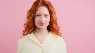 Stüdyoda kameranın önünde pembe arka planda yalnız başına durmuş gülen genç, pozitif bir kadın..