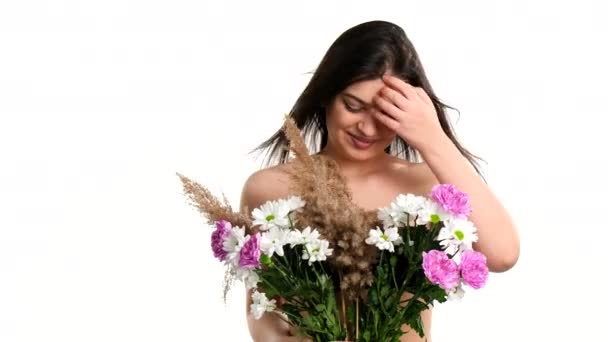 Elégedett barna fiatal nő csupasz mellű borított csokor mezei virágok megérinti a haját fúj a szél. — Stock videók