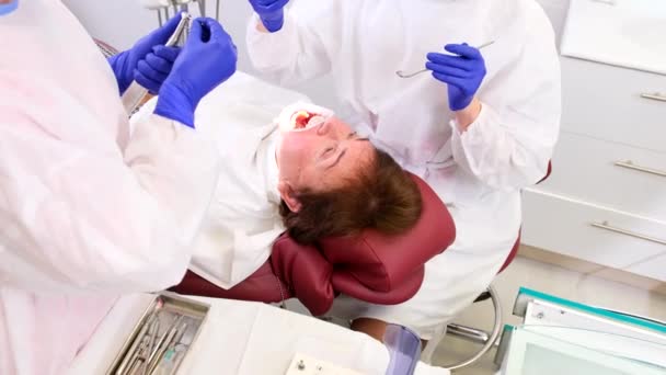 Stomatoloji kliniğinde kadın ağız sağlığı tedavisine yardımcı olan profesyonel dişçi. — Stok video