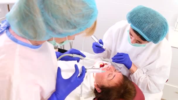 Wanita tua pasien terbaring di kursi dokter gigi dengan mulut terbuka sementara dokter gigi merawat kesehatan giginya dengan bantuan asisten. — Stok Video