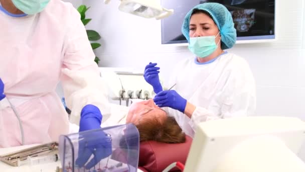 Tandläkare i uniform, medicinska och skyddande handskar ber hennes angripare att ge några verktyg för att arbeta med en patient tänder. — Stockvideo