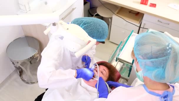 Top view vídeo de dentistas trabalhando com uma assastante ajuda a tratar os dentes das mulheres pacientes enquanto ela está deitada na cadeira do dentista. — Vídeo de Stock