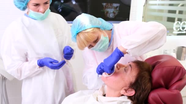 Senior kvinna patient som behandlas av en tandläkare och en angripare både i uniform, medicin hälsa och stomatologi koncept. — Stockvideo