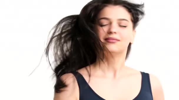 Hezká mladá brunetka žena na bílém pozadí, vítr fouká na její vlasy a ona hraje s tímto pocitem svobody. — Stock video