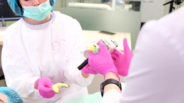 Medic shaping material for dental impression with hands and applies a special toothpaste using stomatological gun. — Stock Video