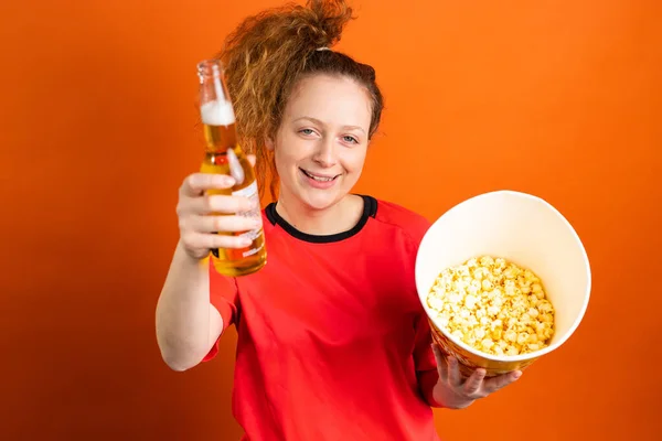Žena fotbalový fanoušek fandit a podporovat její fotbalový tým s lahví piva a popcornu drží v rukou. — Stock fotografie