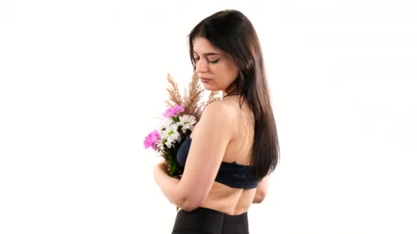 A fiatal hölgy háttal áll a kamerának, aztán megfordul egy csokor virággal a meztelen mellén.. — Stock videók