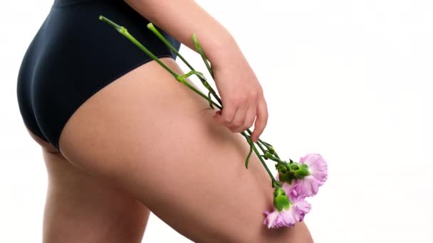 Mujer joven sosteniendo flores sobre el fondo blanco de la ropa interior, cuidado de la salud belleza cuerpo concepto de piel. — Vídeos de Stock