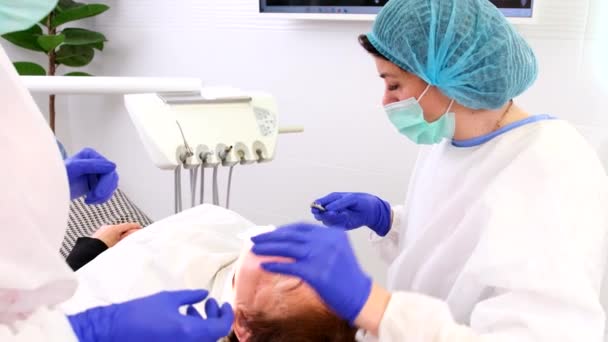 Tıbbi diş hekimi profesyonel bir dişçiye stomatoloji kliniğinde dişlerini tedavi etmesi için bazı aletler veriyor.. — Stok video