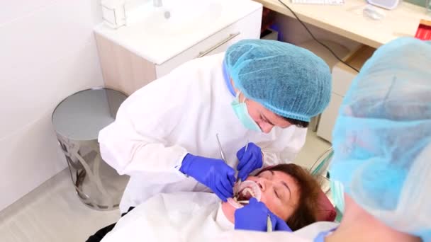 Topp video av en läkare tandläkare med en assistent som arbetar på stomatologisk klinik behandla kvinnliga patienttänder. — Stockvideo