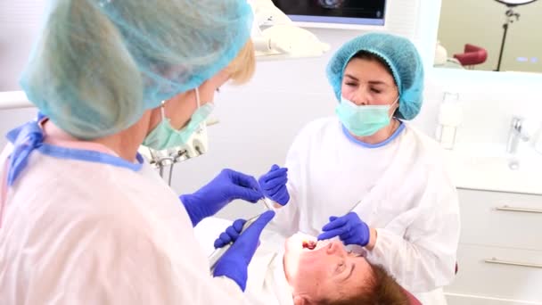 Uma assistente que ajuda o médico dentista com a mudança de ferramentas em seu trabalho com um paciente na clínica estomatológica. — Vídeo de Stock