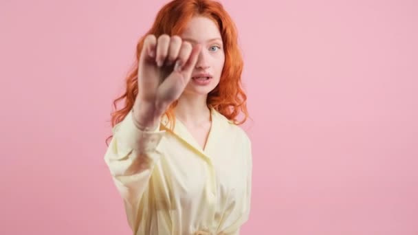 Beautifal young pretty woman with red hair smiling and making knock sign for calling somesody to come and pointing with her hand aside. — Stock Video