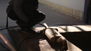 Koruyucu maskeli, eldivenli ve üniformalı bir araba tamircisinin benzin istasyonunda vücut parçalarını kaynak yaparken çekilmiş videosu..