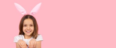 Tavşan kulağı takmış gülümseyen küçük güzel kız pembe arka plan ve fotokopi alanında poz veriyor, Paskalya konsepti tatilinde..