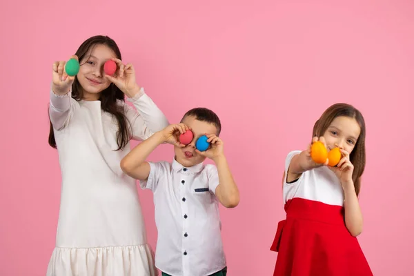 Bild på tre barn som förbereder sig för påskhelgen med målade ägg i händerna och en pojke som täcker sina ögon med ägg och gör narr av varandra. — Stockfoto