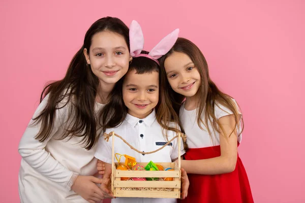 Image de trois enfants adorables de la famille, petit garçon portant des oreilles de lapin et tenant panier d'œufs peints. — Photo