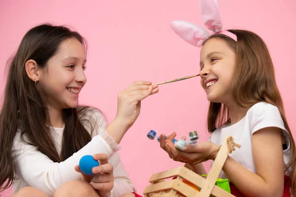 Närbild foto av vackra flickor gör roliga målning näsa och bär kanin öron, förbereda sig för påsk semester. — Stockfoto
