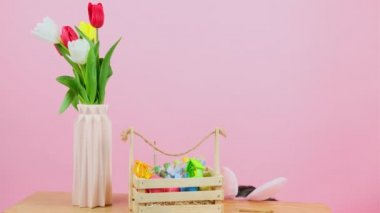 Tavşan kulaklı güzel bir esmer kız saklambaç oynuyor. Sepet dolusu yumurta ve vazoyla oynuyor. Sandalyede şamandıralar var..