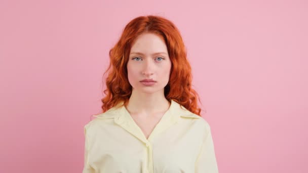 Komoly vörös hajú csinos fiatal nő néz a kamerába, majd ő nevető arckifejezés rózsaszín háttér. — Stock videók