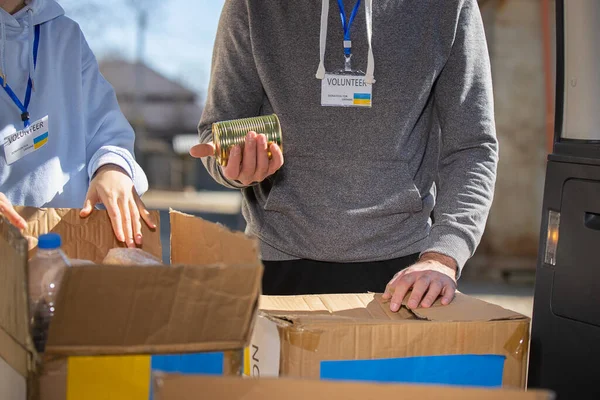 Ukraynalı mülteciler için yiyecek bankasının yanındaki bağış kutularının yanında duran iki gönüllü..