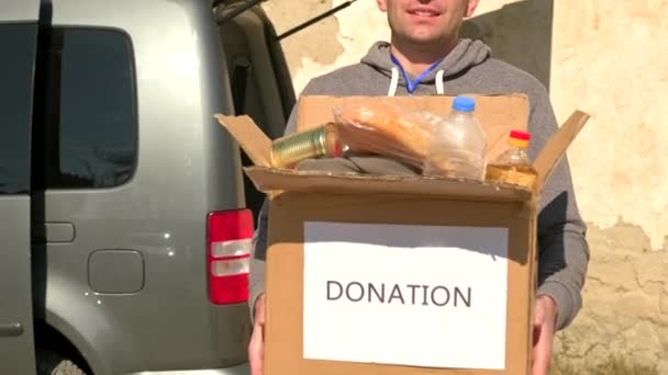 Frivillig man som bär kartongen med mat och dryck för flyktingar som är kvar på gatan. — Stockvideo