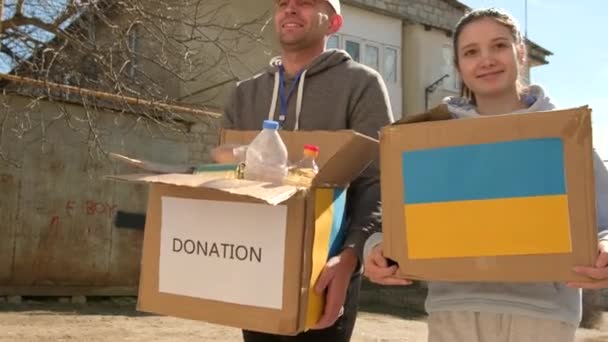 Close up video of volunteers carrying boxes with humanitarian aid for ukrainian refugees in street, charity campaign. — Stock Video