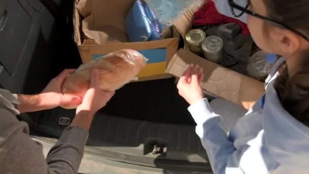 Dois voluntários recolhendo em caixas de papelão doações para as necessidades dos migrantes ucranianos, conceito de ajuda humanitária. — Vídeo de Stock