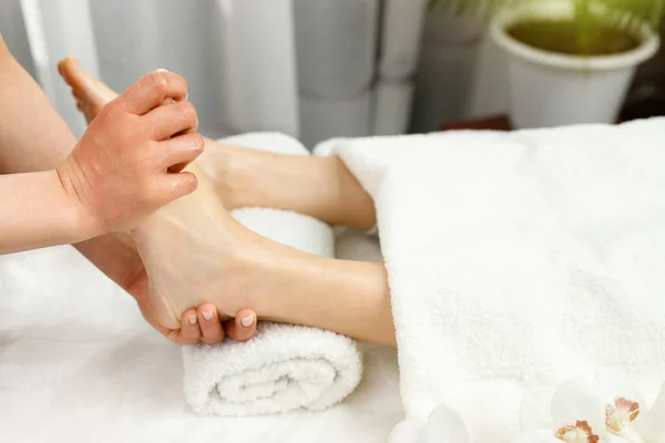 Специалист женщина-массажистка делает массаж ног женщине-клиенту в спа-салон, уход за красотой и здоровье концепции образа жизни. — стоковое фото