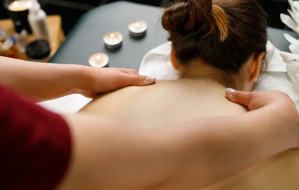 Massaggiatore professionista che fa massaggio alle spalle relax ad una giovane donna sdraiata sul tavolo per un massaggio nel salone spa. — Foto Stock
