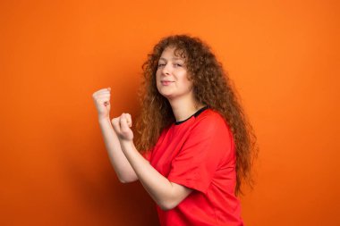 Futbol takımının zaferi ve insani duygular konsepti için yumruklarını tutan, spor formalı, kızıl saçlı güzel bir kadın hayranın fotoğrafı..