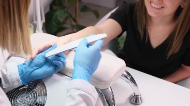 Oříznuté video šťastné a uvolněné klientky, jak dostává pilník nehtů od specialisty na manikúru v salonu krásy. — Stock video