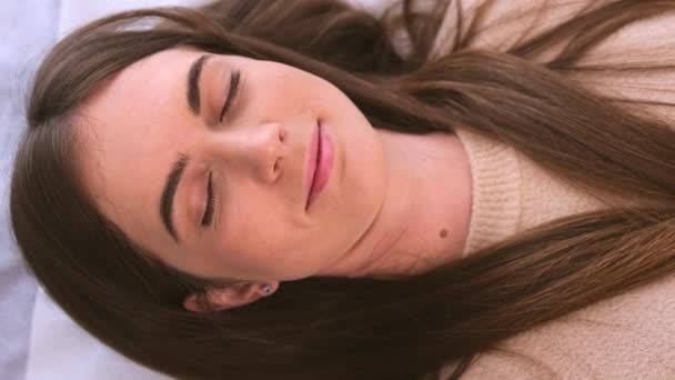 Piękna młoda kobieta odpoczywa z zamkniętymi oczami czekając na kosmetologa, który wykona zabieg odmładzania twarzy. — Wideo stockowe