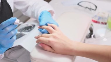 Usta manikür ve masajdan sonra pipetle aromatik yağ sürüyor. Genç kadın parmağı, tırnak bakımı konsepti.. 