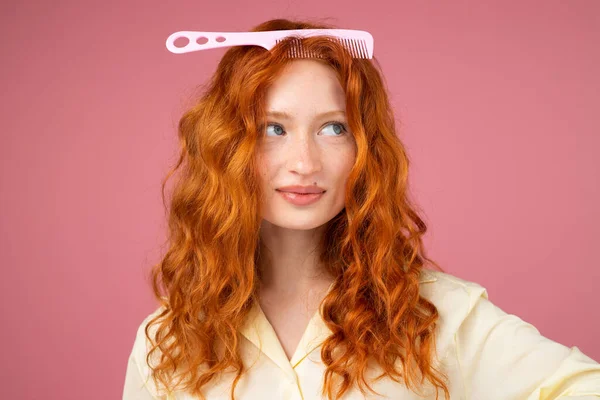 Joyeux jeune rousse femme aux yeux bleus s'amuser et garder un peigne sur la tête dans un salon de beauté. — Photo